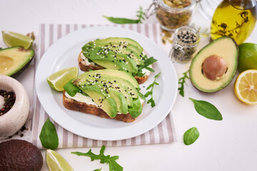 Freshly made Avocado and cream cheese toasts on a white ceramic plate and ingredients