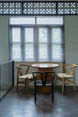 The wooden table and chairs near the window in cafe with sunlight through the window blind sunshade. Empty chairs and table with light and shadow in the room.