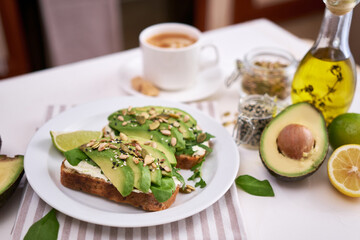 Freshly made Avocado and cream cheese toasts on a white ceramic plate and ingredients