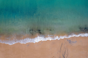 Aerial top down view on a beautiful beach and ocean surface with blue water. Keem bay, Ireland. Nature scene.