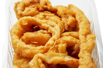 Close up of onion rings in a plastic tray on white background. Simple food with high calorie and fat count. Beer snack.