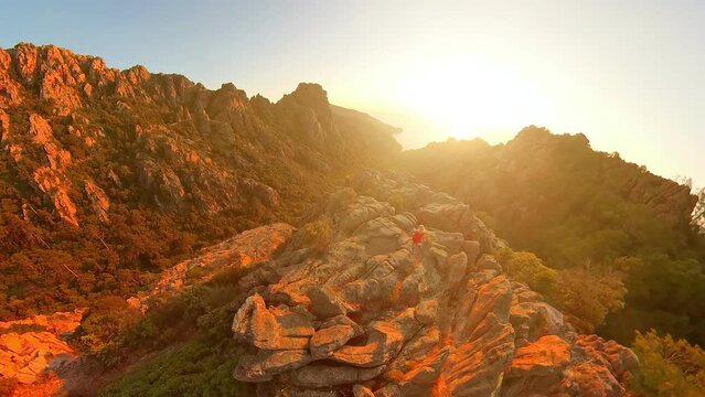 Aerial view of a tourist woman on top of of badlands Calanques of Piana at sunset. Drone view on the road in Corsican badlands called Les Calanques in Mediterranean sea by the Porto Ota
