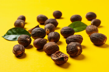 Nutmegs and leaves on yellow background, close up