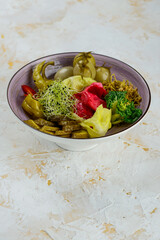 various pickled tomatoes, green capers and cabbage in a plate on a white background
