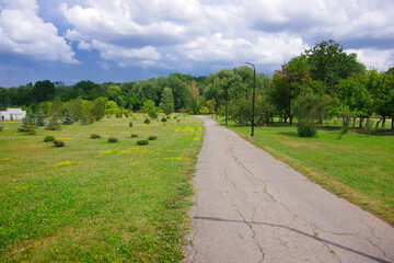 Path in spring park among green trees.
