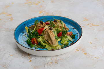 pate with microgreen cones, spinach and bruschetta in a blue plate on a white background
