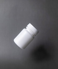 White plastic pill bottle, unlabelled, capped, floating on a black background.