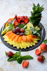 sliced ​​fruits in a large black plate on a white background with berries vertical photo
