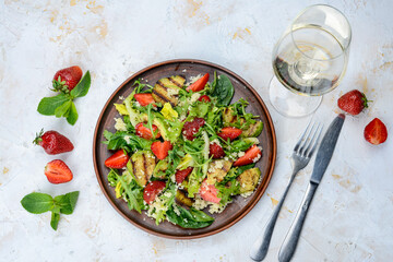 fresh salad with grilled avocado and strawberries and couscous porridge in a clay plate on a white background
