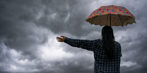 Girl with umbrella watching rain-storm in the distanant landscape.Woman holding an umbrella on a...