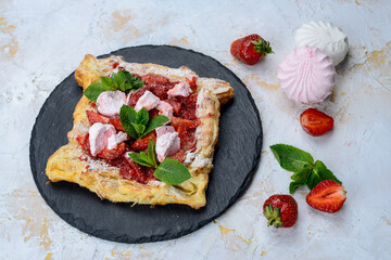 puff pastry with cheese and strawberries in a white plate on a white background with marshmallows and strawberries
