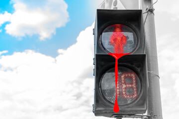 A red traffic light for pedestrians against a blue sky cries blood for the dead. Copy space
