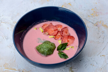 strawberry cream soup with strawberries in a blue plate on a light background
