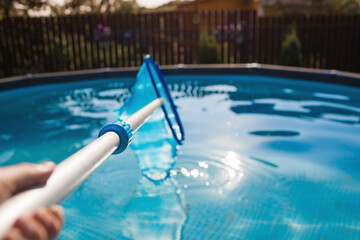 Cleaning of a swimming pool with a metal frame with a mesh from dirt. Pool cleaner during...