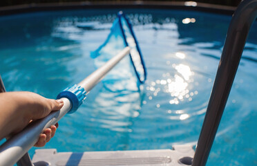 Cleaning of a swimming pool with a metal frame with a mesh from dirt. Pool cleaner during...