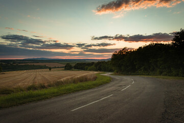 Asphalt road and fields in the Hungarian countryside at dusk