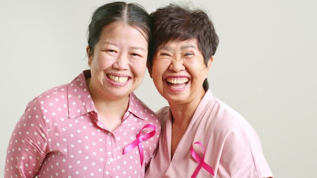 Couple of Asian mother and daughter in pink shirt and pink ribbon for October breast cancer awareness month