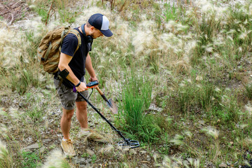 metal detector at work in the forest or field. Search for treasure and ancient values. Archeology. Man with a metal detector. Minesweeper Image