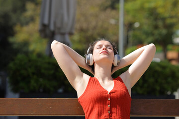 Woman relaxing listening to music sitting in a bench