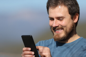 Happy man using mobile phone a sunny day