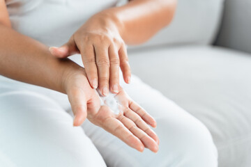 Woman applying body lotion moisturizer on her hands.