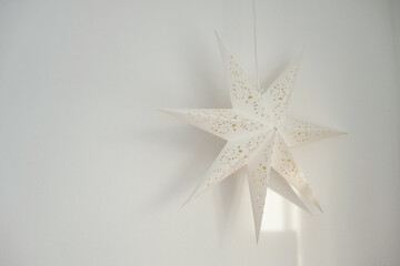 A paper star hangs on a white wall background