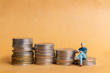 Miniature people, Businessman sitting on coins stack, Financial Concept
