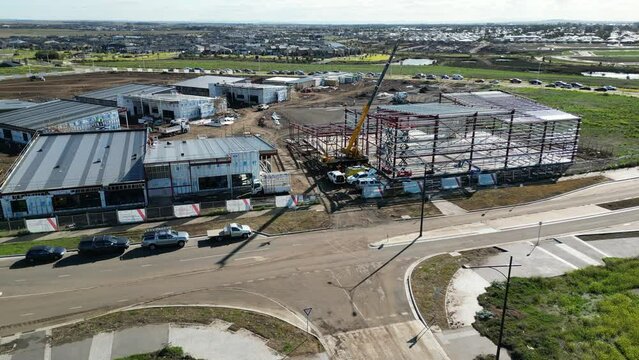 Areal footage of Construction site in Melbourne west crane working on new shopping centre on a nice day with lots of cars DJI drone mud on the road