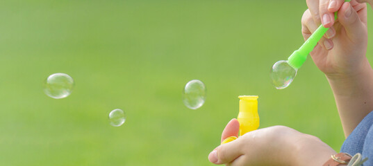 Girl blowing soap bubbles outdoors.  屋外でシャボン玉を吹く女の子 - obrazy, fototapety, plakaty