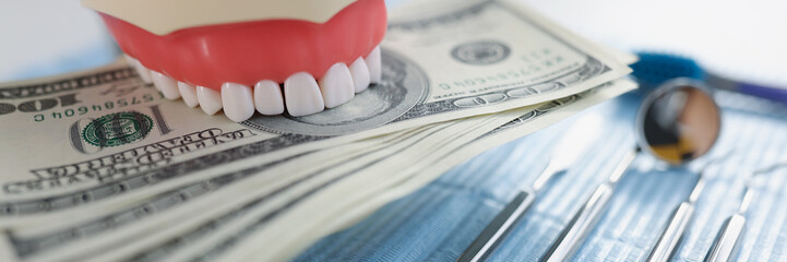 Model teeth lie on a stack of dollars, close-up