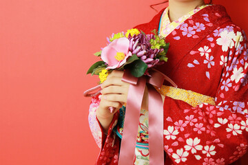 赤い着物を着て花を持つ女性