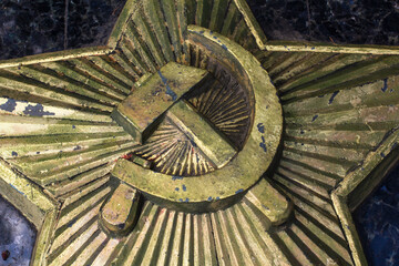 Image of a hammer and sickle on a pentagonal star of the USSR period. Metal bas-relief on marble close-up. Berel Dismantled in 2022 after the Russian invasion of Ukraine
