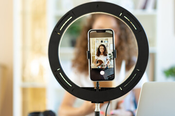 Young curly female blogger recording video at table at home