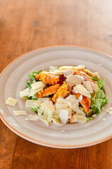 Caesar salad with lettuce,chicken ,parmesan cheese and croutons on wooden table in  a beach restaurant