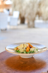 Caesar salad with lettuce,chicken ,parmesan cheese and croutons on wooden table in  a beach restaurant