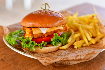 Delicious  Chicken Burger  with bacon, cheddar ,egg  and home made french fries from organic potatoes on wooden table 