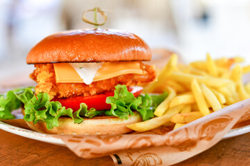 Delicious  Chicken Burger  with bacon, cheddar ,egg  and home made french fries from organic potatoes on wooden table 