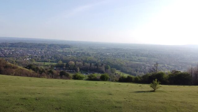 Aerial rotating view of green plains and descending on people in Reigate Hills under