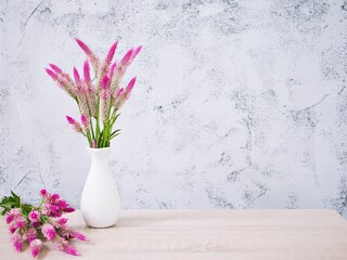 Pink flowers in vase on table with white cement wall texture background or wallpaper, copy space...