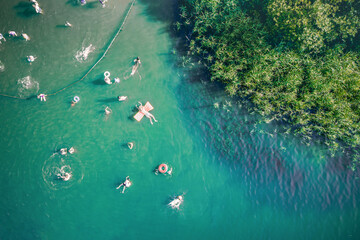 Aerial drone top down view of unrecognizable people swimming in lake. Beautiful blue water with...