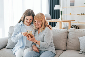 Using smartphone. Mother and daughter is together at home