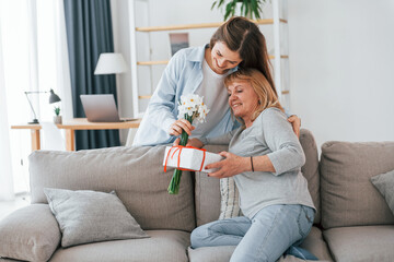 Flowers and present. Happy mother's day. Senior woman and daughter is together at home