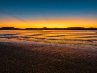 Fototapeta premium Aerial sunrise seascape with orange glow on a cold Winter's morning
