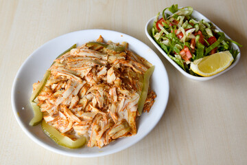 Turkish and Arabic Traditional Ramadan chicken doner kebab with tasty tomato sauce and rice or turkish pilav in white plate on wood table background. (Pilav ustu tavuk doner)