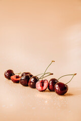 A large cherry with water drops close up on a light orange background in sunlight, selective focus. Front view