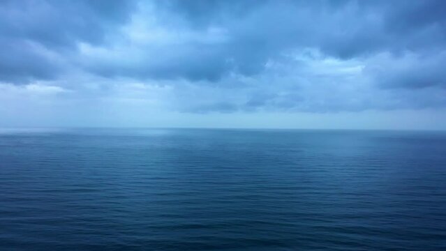 Slow motion of disturbed blue ocean waves at evening with cloudy sky.