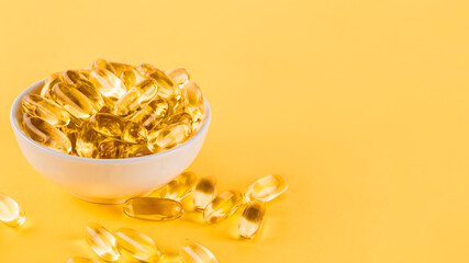 Omega 3 capsules lying on yellow background. Fish oil in pills. Health support and treatment. Biologically active additives. Selective focus.
