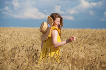 Happy red-haired woman posing in a wheat field