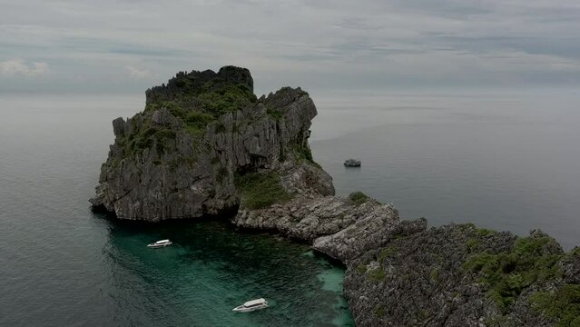 Ang Thon aerial drone film of small rocky island - drone circeling island with anchored boats at shore line  - Thaialnd
