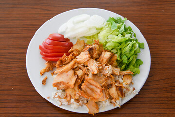 Turkish and Arabic Traditional Ramadan chicken doner kebab with tasty tomato sauce and rice or turkish pilav in white plate on wood table background. (Pilav ustu tavuk doner)